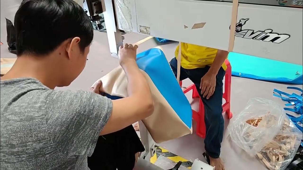 Team members handling blue inflatable material at a workshop machine